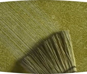 Paint brush applying green paint to a wall